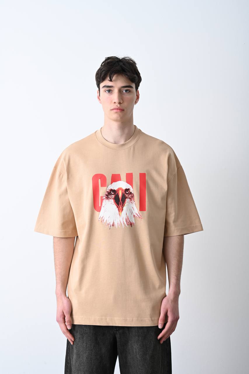 Camel oversize tişört üzerindeki kartal baskısı, özgün ve güçlü bir görünüm sunarak unisex kullanıcılar için şık bir seçim olur.