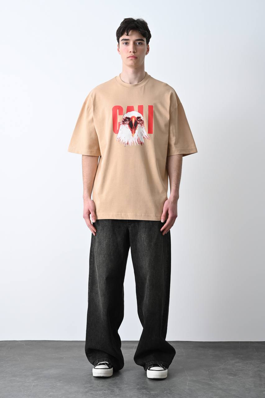 Camel oversize tişört üzerindeki kartal baskısı, özgün ve güçlü bir görünüm sunarak unisex kullanıcılar için şık bir seçim olur.