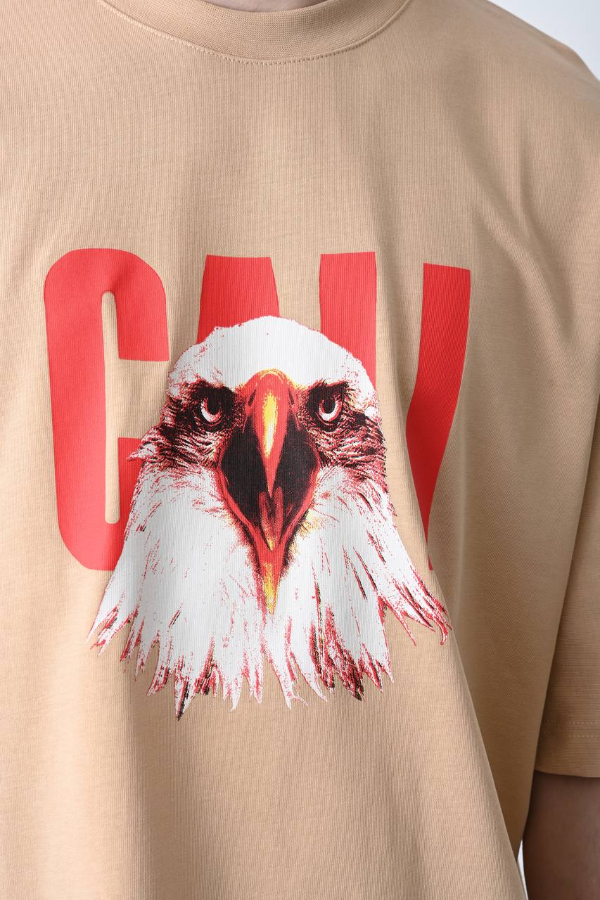 Camel oversize tişört üzerindeki kartal baskısı, özgün ve güçlü bir görünüm sunarak unisex kullanıcılar için şık bir seçim olur.